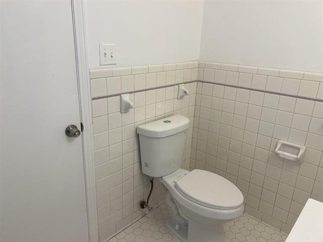 760 E Mckellar Ave, Memphis, TN 38106 - bathroom featuring tile walls, tile patterned floors, toilet, and wainscoting