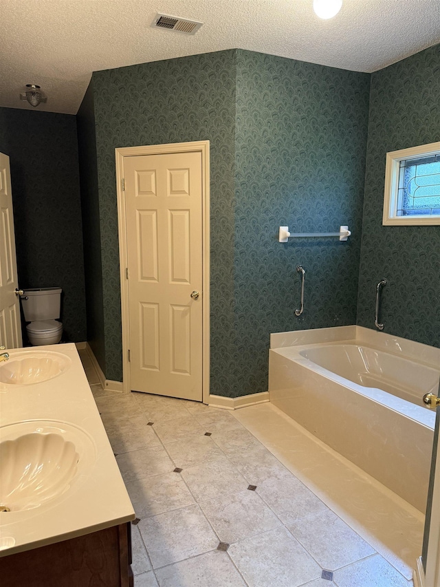 917 Valleyview Ln, Collierville, TN 38017 - bathroom with a garden tub, a textured ceiling, double vanity, tile patterned flooring, and baseboards