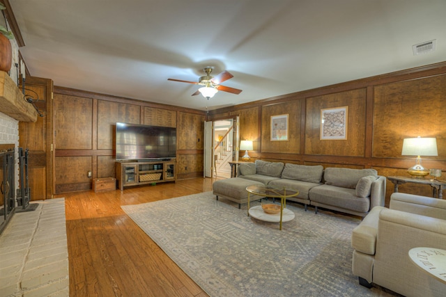 7352 Magnolia Ridge Dr, Germantown, TN 38138 - living area featuring a fireplace, ceiling fan, light wood-style flooring, wood walls, and stairs