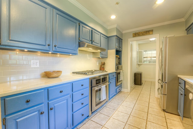 7352 Magnolia Ridge Dr, Germantown, TN 38138 - kitchen with appliances with stainless steel finishes, blue cabinets, under cabinet range hood, backsplash, and light tile patterned floors