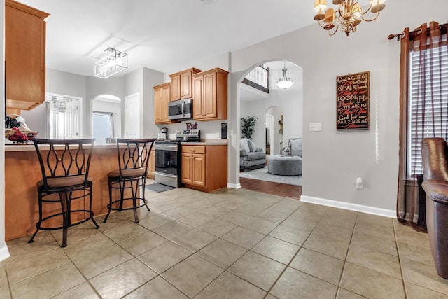 5578 Southern Winds Dr, Arlington, TN 38002 - kitchen with stainless steel appliances, arched walkways, light tile patterned floors, a kitchen breakfast bar, and a chandelier