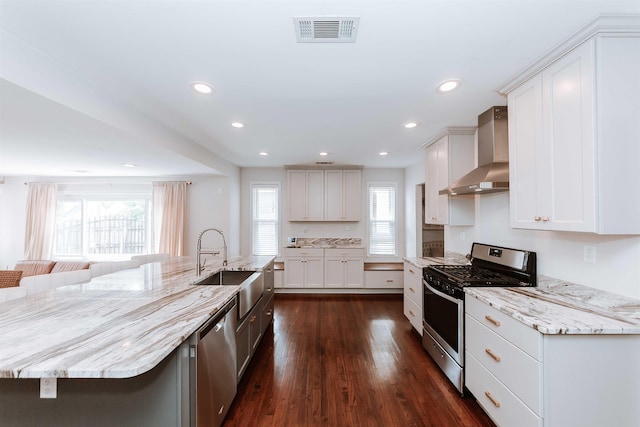 470 N Highland St, Memphis, TN 38122 - kitchen featuring stainless steel appliances, wall chimney exhaust hood, a sink, dark wood finished floors, and light stone counters