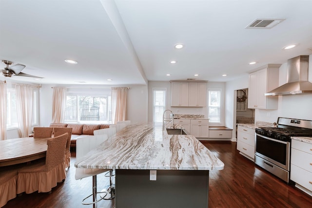470 N Highland St, Memphis, TN 38122 - kitchen with stainless steel gas stove, wall chimney range hood, a sink, a kitchen bar, and light stone counters