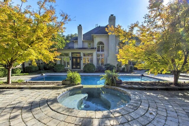9200 Forest Hill Ln, Germantown, TN 38139 - rear view of property with an in-ground hot tub, french doors, an outdoor pool, and a chimney