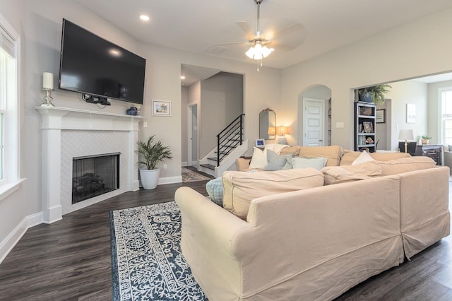 128 Loch Haven Cv S, Atoka, TN 38004 - living area featuring a tiled fireplace, wood finished floors, arched walkways, stairs, and baseboards