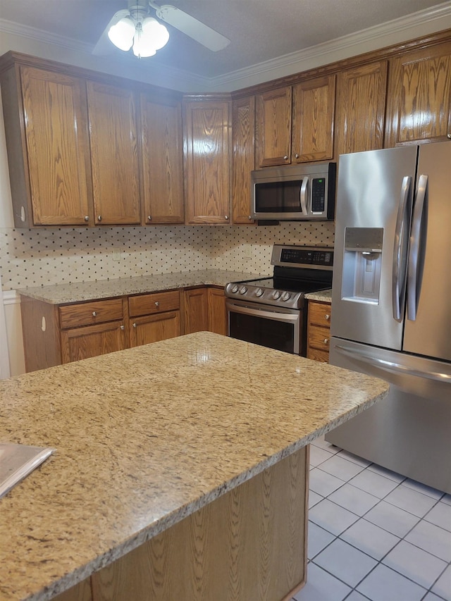 3659 Stonetrace Cir, Bartlett, TN 38135 - kitchen with stainless steel appliances, crown molding, light tile patterned floors, light stone counters, and brown cabinets