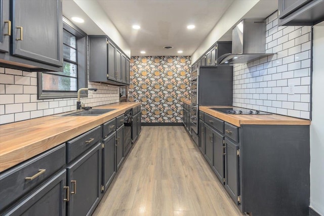 268 Tara Cv, Hernando, MS 38632 - kitchen with butcher block countertops, wall chimney range hood, black electric stovetop, light wood-style flooring, and a sink
