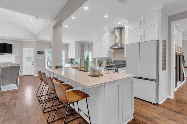 12262 Kathleen Cv, Arlington, TN 38002 - kitchen featuring stainless steel gas range oven, wall chimney range hood, freestanding refrigerator, white cabinets, and recessed lighting