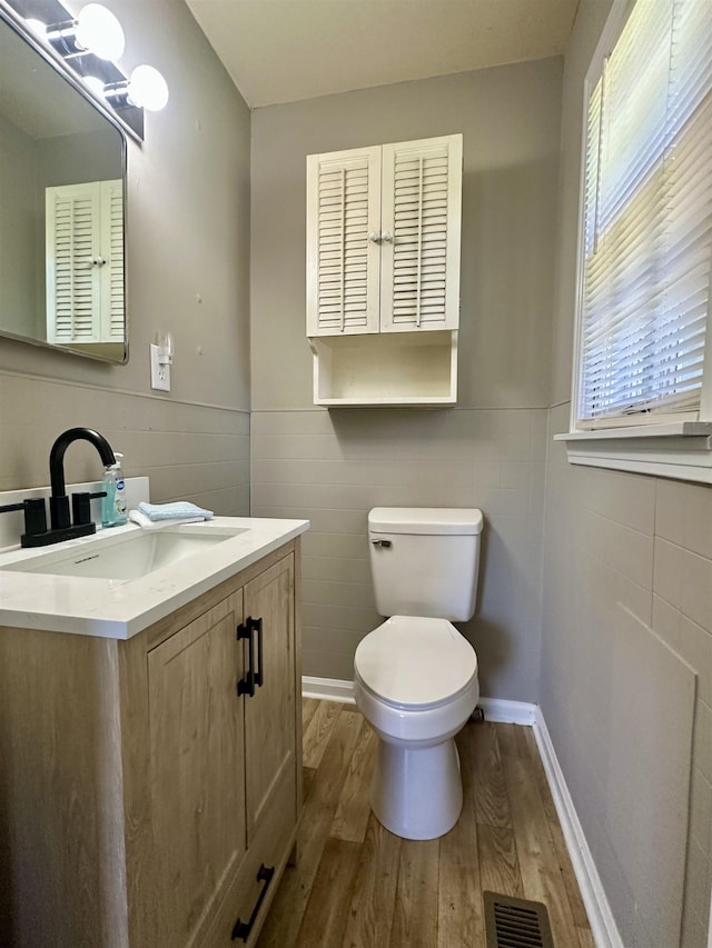 159 Hillhurst Dr, Selmer, TN 38375 - half bath featuring wood finished floors, tile walls, vanity, toilet, and wainscoting