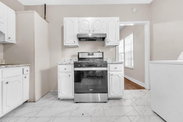 1148 Rozelle St, Memphis, TN 38106 - kitchen featuring extractor fan, stainless steel range with gas stovetop, washer / dryer, light marble finish flooring, and white cabinets