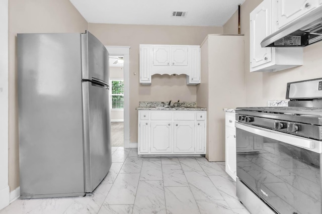 1148 Rozelle St, Memphis, TN 38106 - kitchen with stainless steel appliances, under cabinet range hood, light marble finish floors, and white cabinets