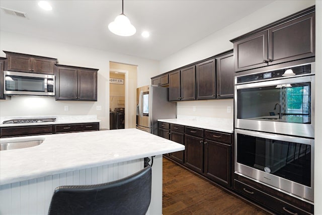 4510 Windway Cv, Bartlett, TN 38135 - kitchen featuring appliances with stainless steel finishes, washing machine and dryer, dark brown cabinetry, light countertops, and dark wood-style flooring