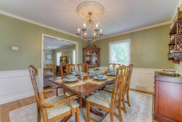 4834 Welchshire Ave, Memphis, TN 38117 - dining area with a chandelier, a wainscoted wall, light wood-style floors, ornamental molding, and a decorative wall