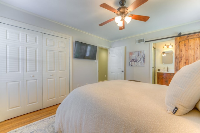 4834 Welchshire Ave, Memphis, TN 38117 - bedroom featuring wood finished floors, a barn door, ornamental molding, a closet, and a sink