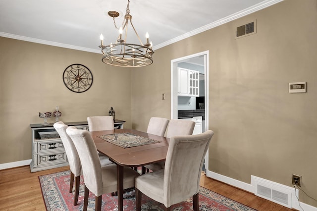 4141 Sequoia Ave, Memphis, TN 38117 - dining area with a chandelier, light wood-type flooring, crown molding, and baseboards
