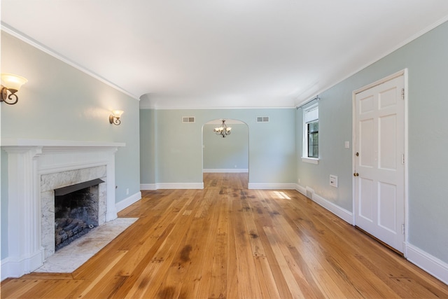 1021 N Barksdale St, Memphis, TN 38107 - unfurnished living room with hardwood / wood-style floors, arched walkways, crown molding, a fireplace, and a chandelier