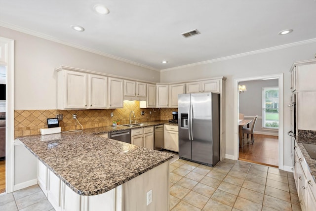 2045 Gallina Cir, Collierville, TN 38017 - kitchen with appliances with stainless steel finishes, a peninsula, dark stone counters, light tile patterned flooring, and backsplash