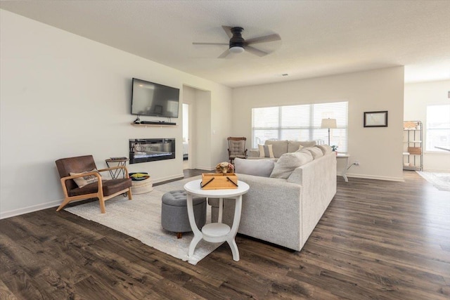 52 Twin Lakes Dr, Byhalia, MS 38611 - living room featuring dark wood-style flooring, a ceiling fan, a glass covered fireplace, and baseboards