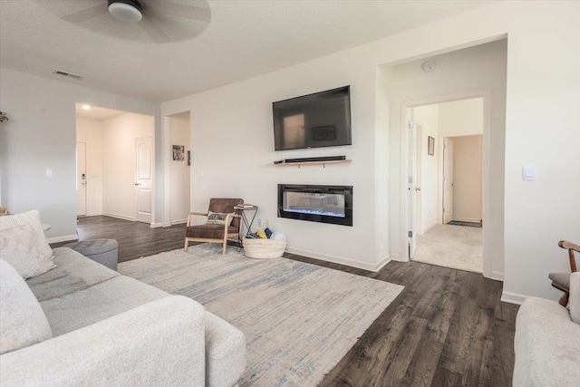 52 Twin Lakes Dr, Byhalia, MS 38611 - living room featuring a glass covered fireplace, dark wood finished floors, a ceiling fan, and baseboards