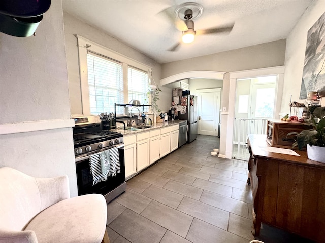 260 N Willett St, Memphis, TN 38112 - kitchen featuring appliances with stainless steel finishes, a sink, a ceiling fan, white cabinets, and arched walkways