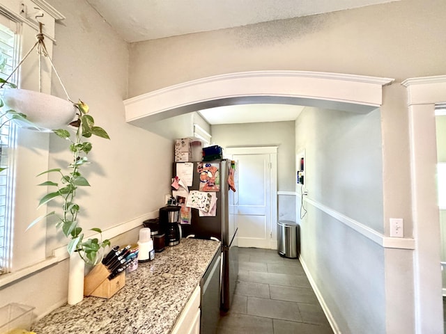 260 N Willett St, Memphis, TN 38112 - kitchen featuring arched walkways, dark tile patterned floors, freestanding refrigerator, light stone countertops, and baseboards