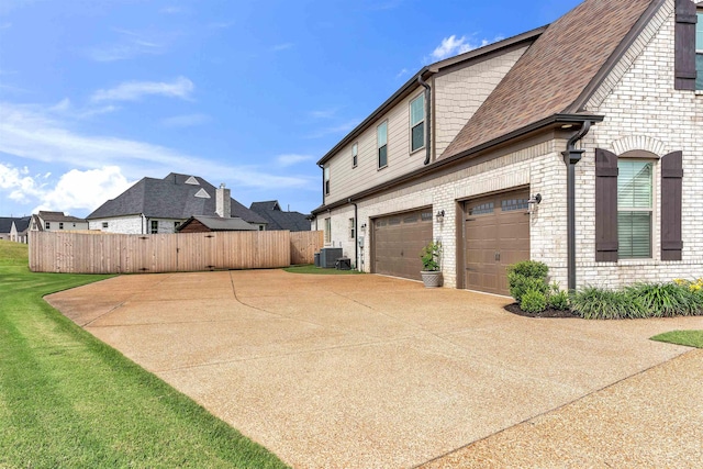 45 Laurel Hedge Cv, Oakland, TN 38060 - view of property exterior with an attached garage, driveway, central air condition unit, brick siding, and roof with shingles