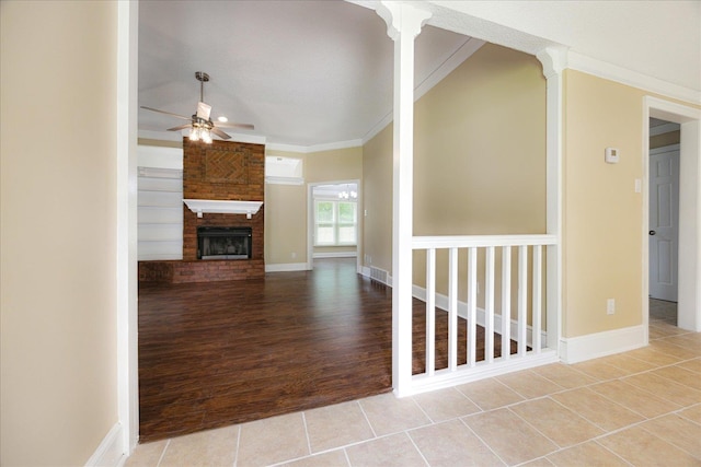4386 S Germantown Rd, Memphis, TN 38125 - unfurnished living room featuring a ceiling fan, a brick fireplace, crown molding, tile patterned flooring, and baseboards