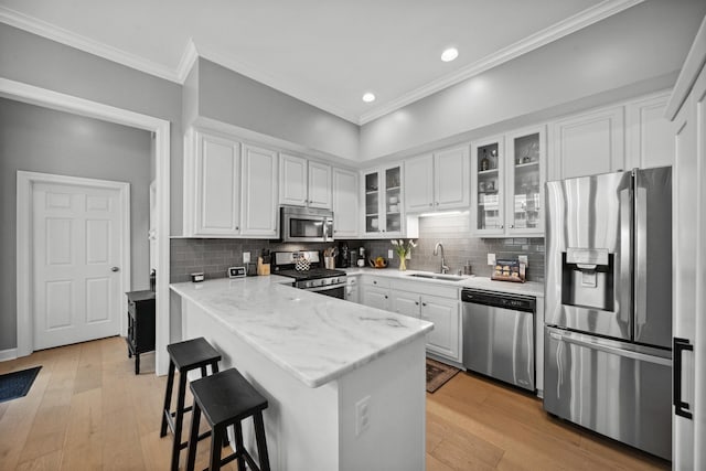 142 Granehampton Ln, Memphis, TN 38111 - kitchen with stainless steel appliances, a sink, a peninsula, white cabinetry, and crown molding