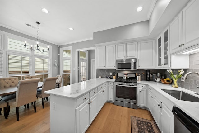 142 Granehampton Ln, Memphis, TN 38111 - kitchen featuring stainless steel appliances, a sink, a peninsula, a chandelier, and light wood finished floors