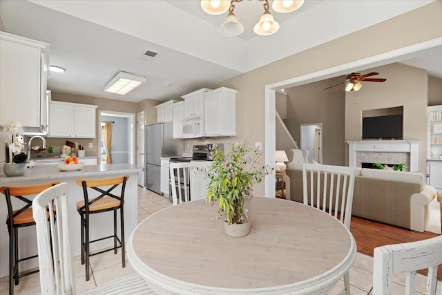 9270 Durhamshire Dr, Cordova, TN 38016 - dining area with light tile patterned floors, a fireplace, a ceiling fan, and a chandelier