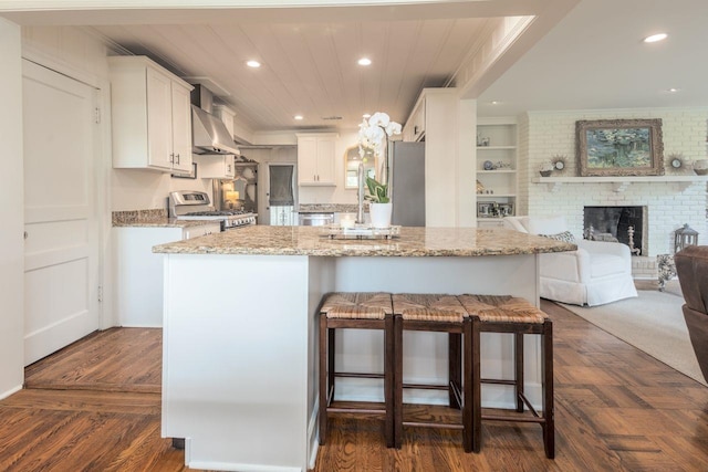 241 Greenway Rd, Memphis, TN 38117 - kitchen with appliances with stainless steel finishes, open floor plan, wall chimney range hood, white cabinets, and a kitchen breakfast bar