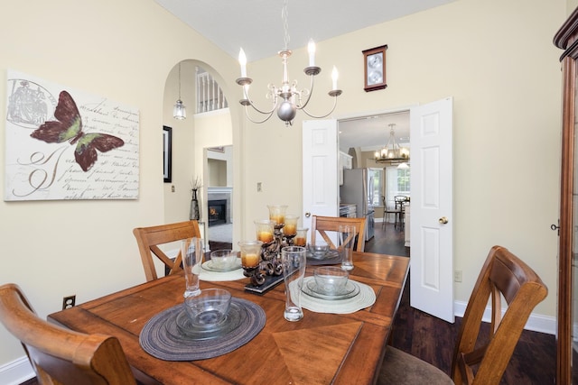 4528 Queen Sinclair Cir, Millington, TN 38053 - dining area featuring a chandelier, wood finished floors, a warm lit fireplace, arched walkways, and high vaulted ceiling