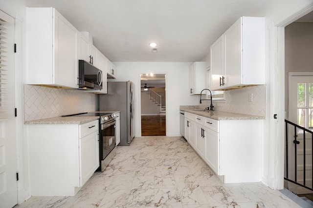 5236 Marynelle Cv, Memphis, TN 38116 - kitchen with appliances with stainless steel finishes, a sink, light marble finish floors, and decorative backsplash