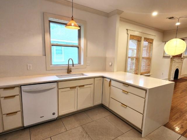 1466 Snowden Ave, Memphis, TN 38107 - kitchen with white dishwasher, a sink, ornamental molding, light countertops, and plenty of natural light