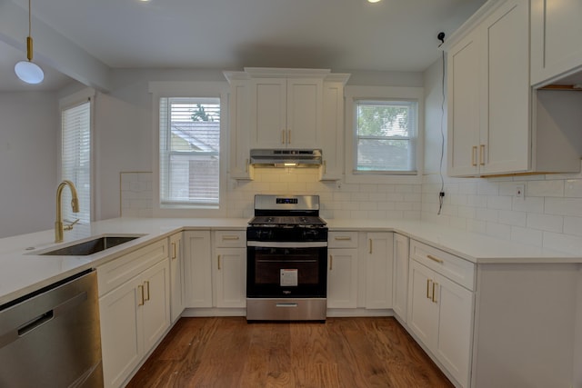 857 E Parkway St, Memphis, TN 38104 - kitchen featuring appliances with stainless steel finishes, under cabinet range hood, a sink, dark wood-style floors, and decorative backsplash
