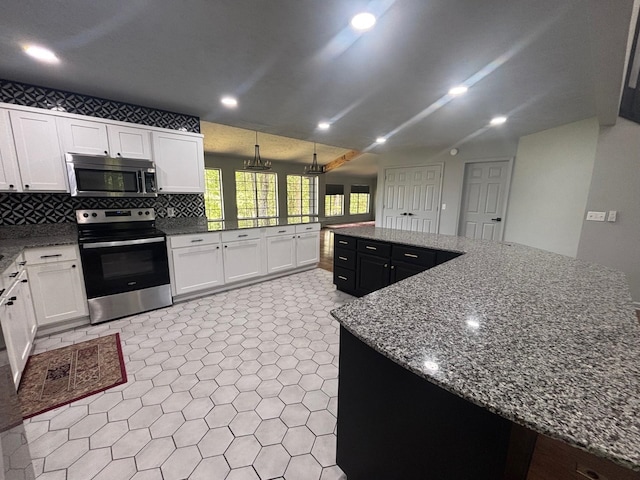 245 Holiday Hills Ln, Counce, TN 38326 - kitchen featuring appliances with stainless steel finishes, white cabinetry, dark stone countertops, tasteful backsplash, and a spacious island