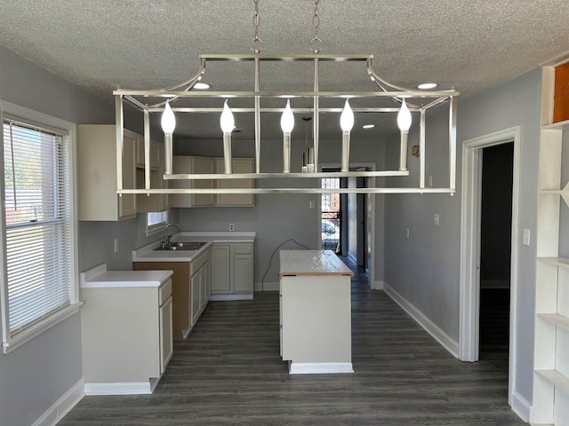 1058 Seymour St, Memphis, TN 38108 - kitchen with a textured ceiling, baseboards, a sink, dark wood-type flooring, and a kitchen island