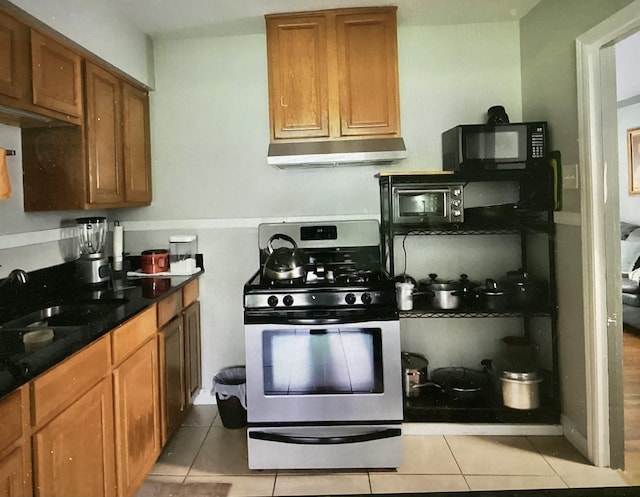 4864 Bowen Ave, Memphis, TN 38122 - kitchen with stainless steel range with gas cooktop, black microwave, under cabinet range hood, a sink, and brown cabinetry