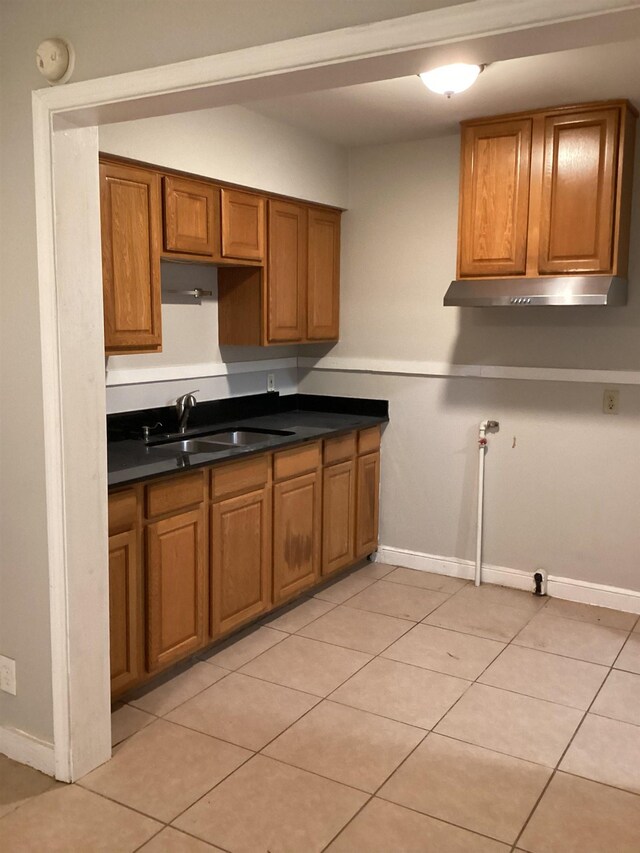 4864 Bowen Ave, Memphis, TN 38122 - kitchen featuring a sink, brown cabinets, under cabinet range hood, and dark countertops
