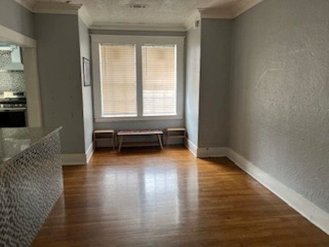 929 N Watkins St, Memphis, TN 38107 - unfurnished dining area featuring ornamental molding, wood finished floors, baseboards, and a textured wall