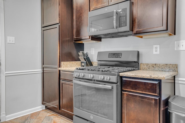 4951 Lynbar Ave, Memphis, TN 38117 - kitchen with appliances with stainless steel finishes, baseboards, light stone counters, and dark brown cabinets