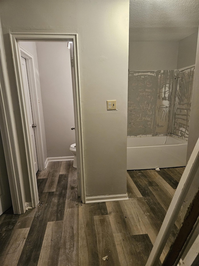 1866 Kansas St, Memphis, TN 38109 - bathroom featuring toilet, wood finished floors, a bath, a textured ceiling, and baseboards