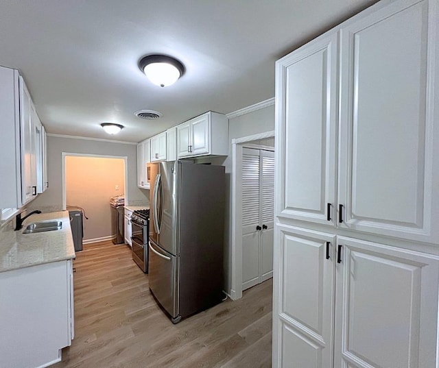 4485 Dunn Rd, Memphis, TN 38117 - kitchen with stainless steel appliances, a sink, light wood-style floors, white cabinetry, and ornamental molding