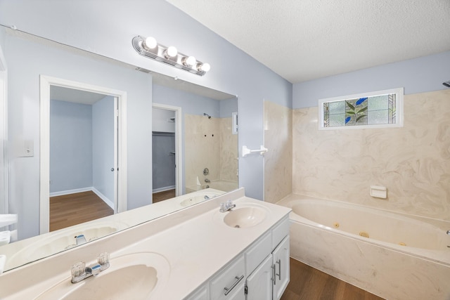 5424 Peyton Randolph St, Bartlett, TN 38134 - bathroom featuring wood finished floors, double vanity, a textured ceiling, and a combined bath / shower with jetted tub