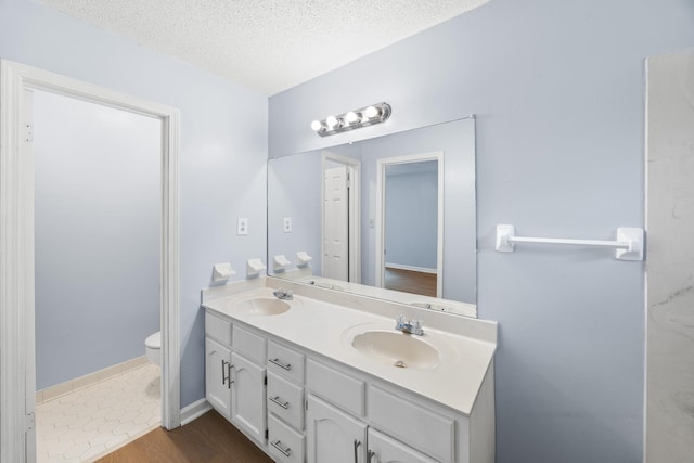 5424 Peyton Randolph St, Bartlett, TN 38134 - full bathroom featuring double vanity, toilet, a textured ceiling, and wood finished floors