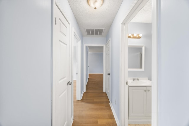 5424 Peyton Randolph St, Bartlett, TN 38134 - corridor featuring a textured ceiling, a sink, baseboards, and light wood finished floors