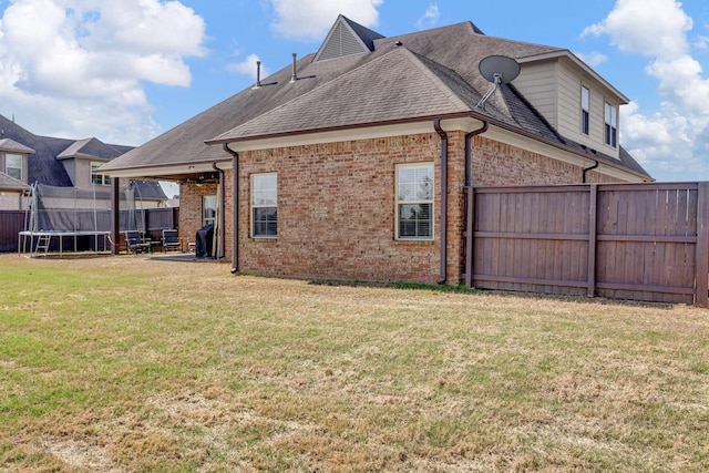 6486 Anglia Valley Dr, Arlington, TN 38002 - rear view of house with a trampoline, brick siding, and roof with shingles