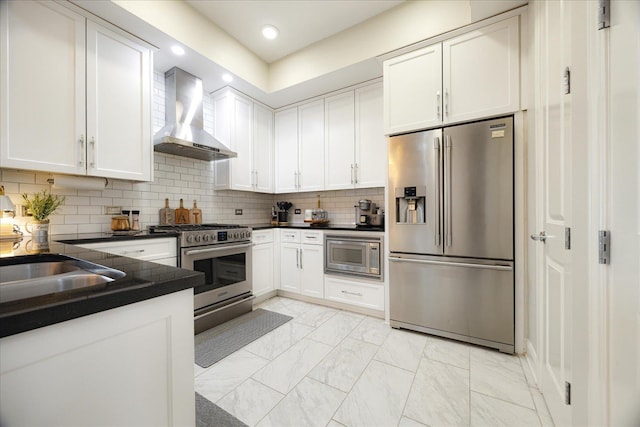 717 Riverside Dr Unit 1104, Memphis, TN 38103 - kitchen with appliances with stainless steel finishes, wall chimney exhaust hood, dark countertops, light marble finish flooring, and white cabinetry