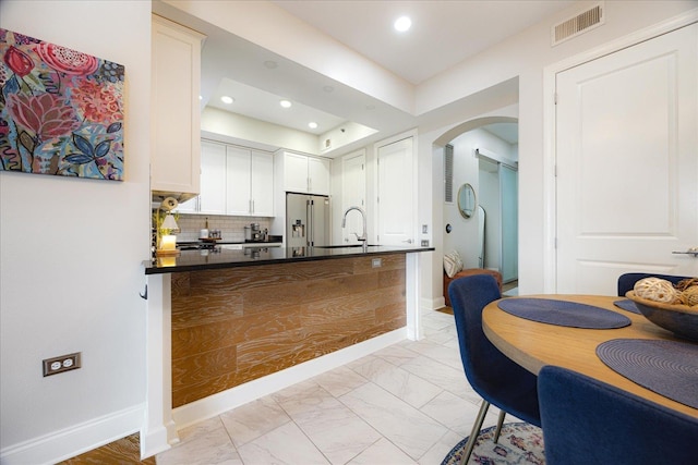 717 Riverside Dr Unit 1104, Memphis, TN 38103 - kitchen featuring high end fridge, dark countertops, light marble finish flooring, arched walkways, and a sink