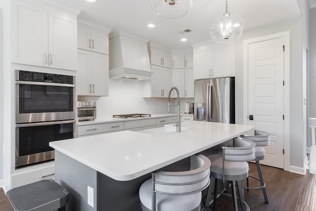 9709 Woodland Brook Ln S, Cordova, TN 38018 - kitchen featuring stainless steel appliances, dark wood finished floors, a breakfast bar area, premium range hood, and recessed lighting